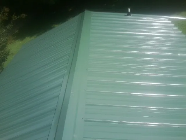 New green metal panels meeting at the ridge of a roof — Flat Roof Repair work by our crew in Catawba
