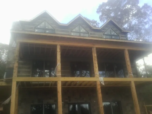 Dormers and porch framing on a large log home under construction — Roof Coating work by our crew in Catawba